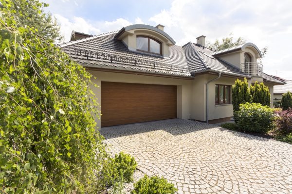Detached family house exterior with cobblestone driveway to the garage and spruce garden
