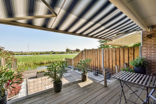 Neat paved patio with sitting area and small garden near wooden fence